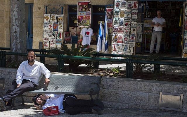 An Orthodox Jewish man hides under a bench as his friend sits and watches in the Jewish Quarter of Jerusalem as sirens are sounded throughout Israel as part of a IDF Home Front Command drill simulating a bomb attack on May 27, 2013. Sarah Schuman/ Flash90)