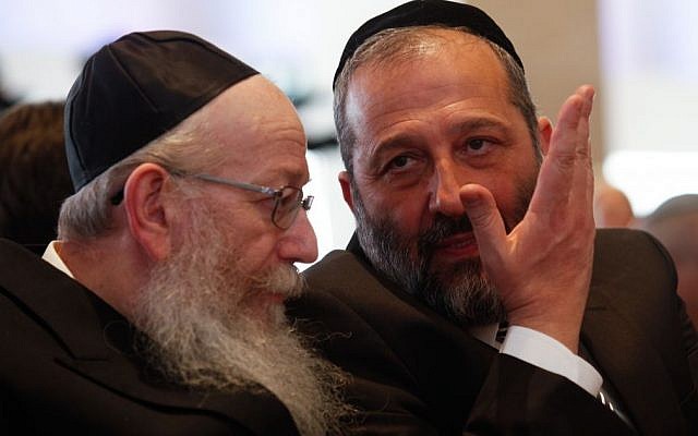 Shas leader MK Aryeh Deri (right) speaks with United Torah Judaism leader MK Yaakov Litzman (left) during the opening session of the 20th Knesset, March 31, 2015. (Nati Shohat/Flash90)