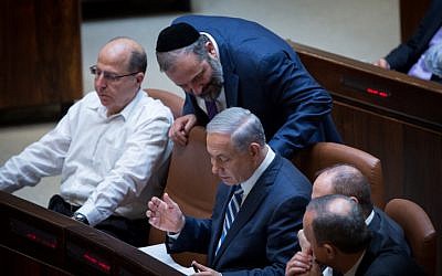 Prime Minister Benjamin Netanyahu speaks with leader of the Shas party, Aryeh Deri, during a plenum session in the Knesset on May 4, 2015. (photo credit: Miriam Alster/Flash90)
