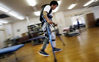 Yuichi Imahata walks using a robotic exoskeleton called ReWalk at Kanagawa Rehabilitation Center in Atgugi, Japan on April 17, 2015. Imahata, 31, has been using a wheelchair to get around for seven years after a serious spinal-cord injury suffered in an accidental fall while working for a transport company.  (Photo credit: Shuji Kajiyama/AP)