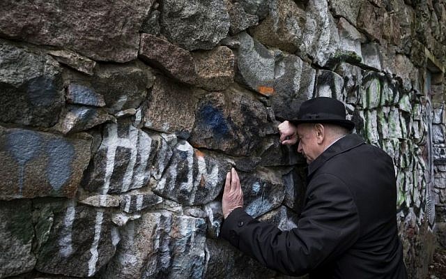 Shmuel Levin, chairperson of the Jewish religious community of Vilnius and Lithuania, leans against a wall of the power substation built of tombstones from a Jewish cemetery in Vilnius, Lithuania, May 13, 2015 (AP/Mindaugas Kulbis)