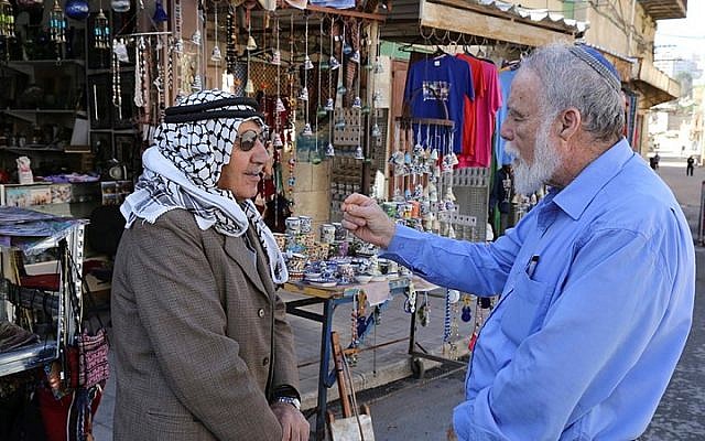 A Palestinian and a Jew seen talking outside a shop near the Cave of the Patriarchs in Hebron, on December 10, 2014. (Gershon Elinson/Flash90)