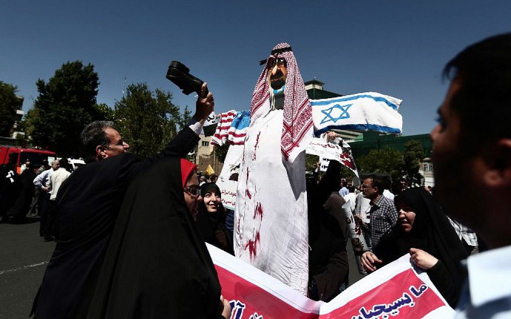An Iranian man beats with his shoe an effigy of a Saudi royal with flags of the United States and Israel attached to it during a demonstration in Tehran on May 8, 2015. (photo credit: AFP/Behrouz Mehri)