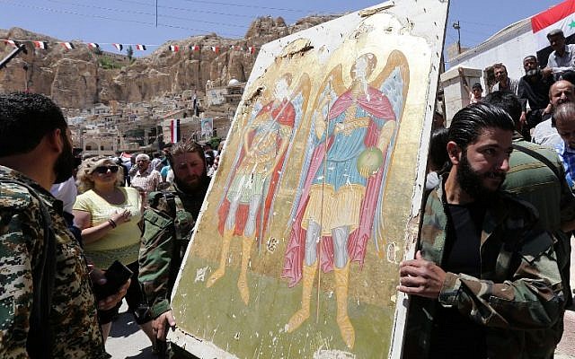 Members of the Syrian National Defense Forces (NDF) carry an icon in order to restore it to its original place on June 13, 2015 in the ancient Christian town of Maaloula, 56 kilometers northeast of the Syrian capital Damascus. (AFP PHOTO / LOUAI BESHARA)