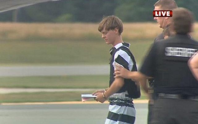 In this screen grab taken from WBTV News, shooting suspect Dylann Roof (L) is escorted by police at the Shelby-Cleveland County Regional Airport for extradition back to Charleston, South Carolina in Shelby, North Carolina on June 18, 2015. (AFP/ WBTV NEWS/ HO)