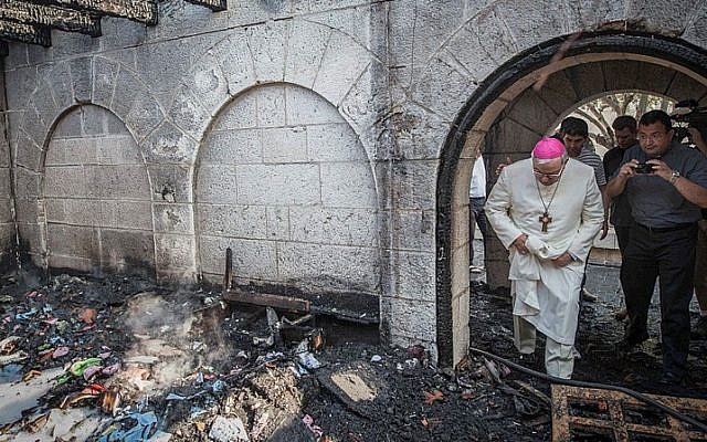 A priest inspects the damage caused to the Church of the Multiplication at Tabgha, on the Sea of Galilee, in northern Israel, which was set on fire in what police suspect was an arson attack, on June 18, 2015. (Basel Awidat/Flash90)