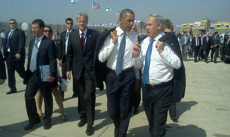 Prime Minister Benjamin Netanyahu and President Barack Obama talk at Ben Gurion Airport after Obama's arrival in Israel in March 2013. Michael Oren walks behind Obama (Via Facebook)