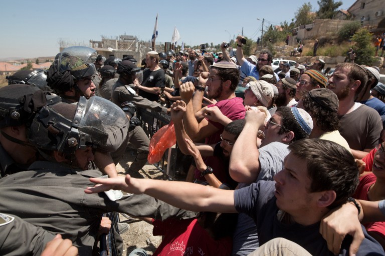 Israeli settlers scuffle with security forces as demolition starts of the Dreinoff buildings in the settlement of Beit El, in the West Bank, on 29 July, 2015. (AFP PHOTO / MENAHEM KAHANA)