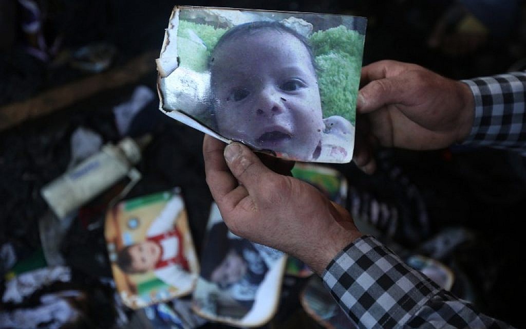 A man shows a picture of 18-month-old Palestinian toddler Ali Saad Dawabsha, who died when his family house was set on fire by alleged Jewish extremists in the West Bank village of Duma, on July 31, 2015. (AFP/Jaafar Ashtiyeh)