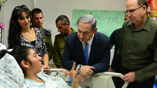 Prime Minister Benjamin Netanyahu and Defense Minister Moshe Ya'alon (right) visiting the border police officer who was stabbed earlier this week by a Palestinian women. (Kobi Gideon/GPO)