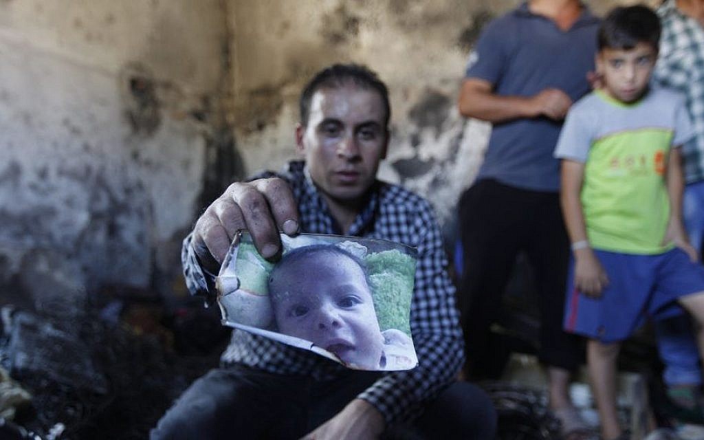 A relative holds up a photo of a one-and-a-half year old boy, Ali Dawabsha, in the family house torched in a suspected attack by Jewish terrorists in Duma village near the West Bank city of Nablus, Friday, July 31, 2015. The boy died in the fire, his parents, badly hurt, also later died. (AP Photo/Majdi Mohammed)