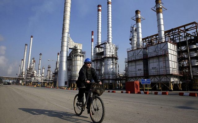 An Iranian oil worker rides his bicycle near an oil refinery south of the capital, Tehran, December 22, 2014. (AP/Vahid Salemi/File)