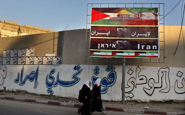 Palestinian school girls pass a billboard covered by national and Iranian flags with Arabic reading 'thanks and gratitude to Iran,' in Gaza City, November 28, 2012 (AP/Adel Hana)
