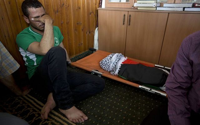 A Palestinian man mourns alongside the body of a one-and-a-half year old boy, Ali Dawabsha, during his funeral in Duma village near the West Bank city of Nablus, Friday, July 31, 2015. (Majdi Mohammed/AP)