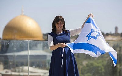 From a vantage point near the Temple Mount, Tzipi Hotovely waves the Israeli flag, with the Dome of the Rock in the background, May 1, 2014. (Yonatan Sindel/Flash90)