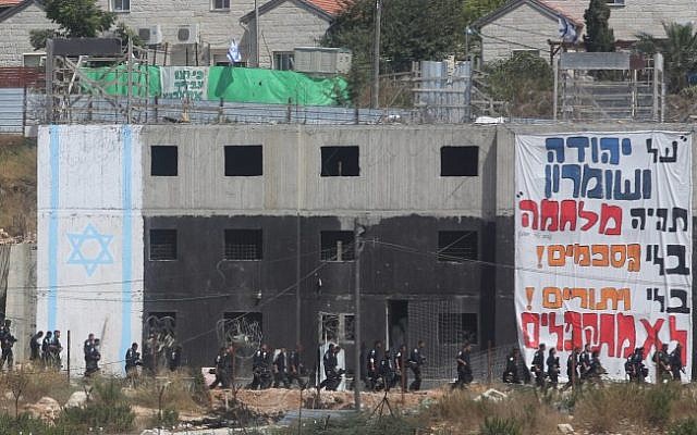 Israeli security forces walk by a building in which Israeli settlers had barricaded themselves to resist an evacuation at the Jewish settlement of Beit El, near the West Bank town of Ramallah on July 28, 2015. (Flash90)