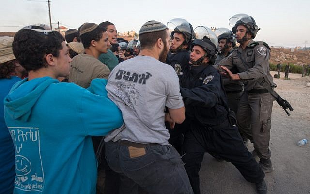 Security forces scuffle with settlers who had barricaded themselves in an attempt to prevent the demolition of illegally constructed buildings, at the Jewish settlement of Beit El, near the West Bank town of Ramallah, on July 28, 2015. (Nati Shohat/Flash90)
