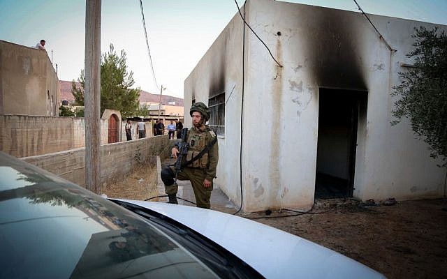 An Israeli soldier stands near a house in the Palestinian village of Duma, near Nablus, where a Palestinian infant was killed July 31, 2015, in an arson attack, apparently by Jewish extremists. (Photo by FLASH90)