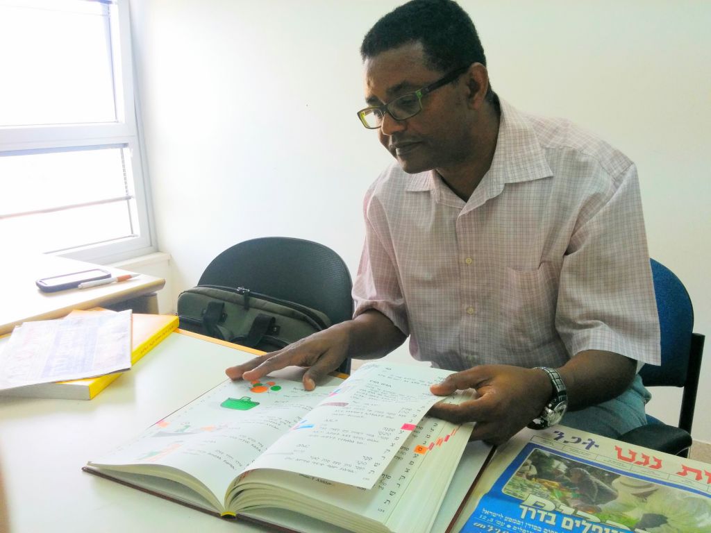 Dr. Anbessa Teferra, a professor of Semitic languages at Tel Aviv University, with an Amharic-Hebrew pictorial dictionary he edited. (Ilan Ben Zion/Times of Israel staff)