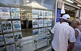 A couple looks at real estate ads in the coastal city of Netanya, July 29, 2015. (AP Photo/Sebastian Scheiner)