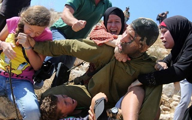 A Palestinian girl (left), bites the hand of an Israeli soldier (center), during clashes between Israeli security forces and Palestinian protesters, in the West Bank village of Nabi Saleh near Ramallah, August 28, 2015. (AFP/Abbas Momani)