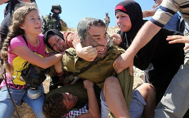 Palestinians fight an Israeli soldier who attempted to arrest a boy at a protest near the West Bank village of Nabi Saleh, near Ramallah, on August 28, 2015. (AFP Photo/Abbas Momani)