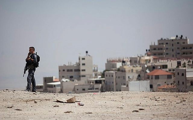 File: A police guard stands near the entrance to the village of Issawiyah on September 9, 2014. (Yonatan Sindel/Flash90)