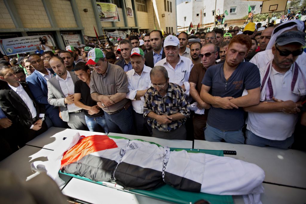 Palestinians prays by the body of Saad Dawabsha, 32, during his funeral procession in the West Bank village of Duma near Nablus on Saturday, Aug. 8, 2015. (AP Photo/Majdi Mohammed)