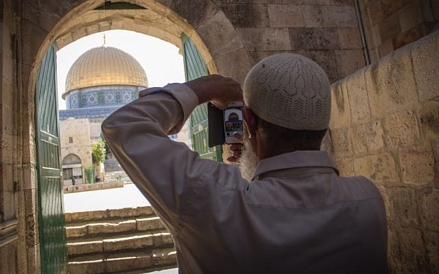 A Muslim man takes a picture of the Dome of the Rock seen through an arch in the Old City of Jerusalem in Israel, July 22, 2015. (Garrett Mills/Flash 90)