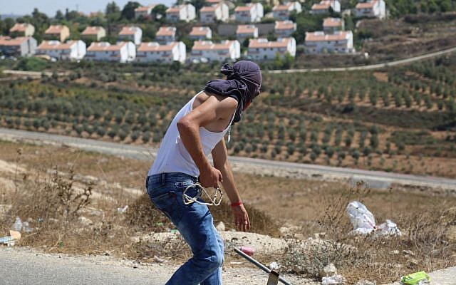 Illustrative: A Palestinian prepares to throw stones at IDF soldiers guarding the Halamish settlement. (Eric Cortellessa/Times of Israel)