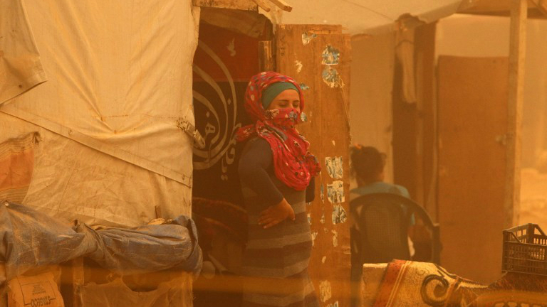 A Syrian woman stands outside her tent surrounded by a cloud of dust during a sandstorm on September 7, 2015 at a refugee camp on the outskirts of the eastern Lebanese city of Baalbek. (AFP Photo/STR)