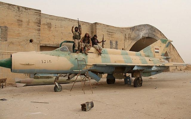 Members of Al-Qaeda's Syrian affiliate and its allies sit on top of a Russian-made former Syrian army fighter jet after they seized the Abu Duhur military airport, the last regime-held military base in northwestern Idlib province on September 9, 2015 (AFP/OMAR HAJ KADOUR)