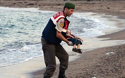 A paramilitary police officer carries the lifeless body of Aylan Kurdi, 3, after a number of migrants died and a smaller number were reported missing after boats carrying them to the Greek island of Kos capsized, near the Turkish resort of Bodrum early Wednesday, Sept. 2, 2015. (AP/DHA)