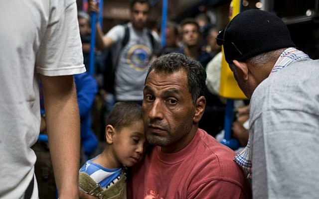 A man and a child ride aboard a bus provided by Hungarian authorities for migrants and refugees at Keleti train station in Budapest, Hungary, Saturday, Sept. 5, 2015. (AP Photo/Marko Drobnjakovic)