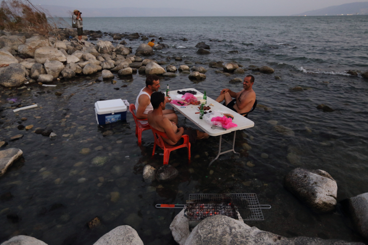 Israelis at Lake Kinneret enjoy a barbecue in the water, August 18, 2014. (Yaakov Naumi/Flash90)