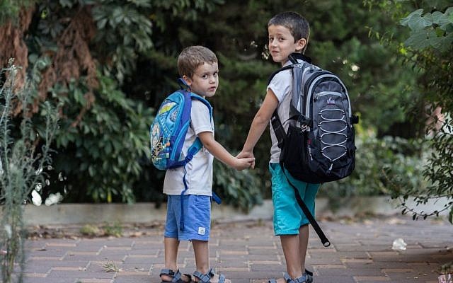 Israeli kids wearing backpacks for the first day of school and kindergarten stand outside their home in Jerusalem on August 31, 2015 (Yonatan Sindel/Flash90)