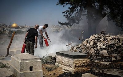 Security personel try to extinguish a fire which broke out at the Jewish cemetery on the Mount of Olives, where several tombstones were allegedly desecrated and set on fire overnight, September 2, 2015 [Hadas Parush/Flash90]
