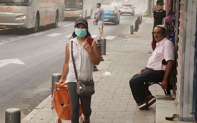 A woman wears a mask to cover her mouth on a dusty day in Tel Aviv September 09, 2015. (FLASH90)