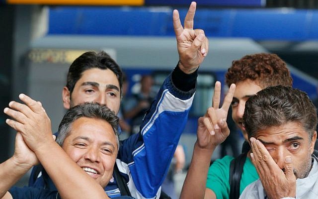 Refugees flash victory signs and wipe away tears as they arrive at the main train station in Munich, Germany, Saturday, Sept. 5, 2015. (AP Photo/Michael Probst)
