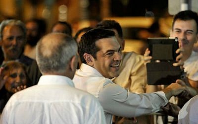 Leader of the left-wing Syriza party Alexis Tsipras shakes hands with a supporter as he arrives at the headquarters of his party in Athens, Sunday, Sept. 20, 2015. (AP Photo/Fotis Plegas G.)