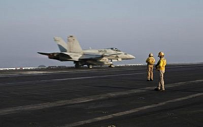 In this Thursday, Sept. 10, 2015 photo, plane directors, wearing yellow jerseys, oversee the takeoff of a US Marine fighter jet aircraft aboard the USS Theodore Roosevelt aircraft carrier, which currently serves as a base for air strikes against Islamic State in Syria. (AP Photo/Marko Drobnjakovic)