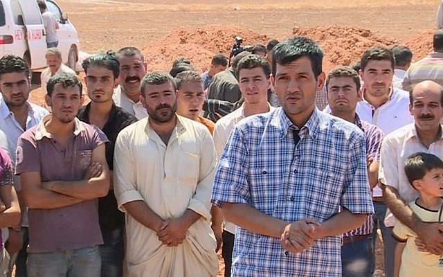 In this image made from video, Abdullah Kurdi, foreground, the Syrian man who survived a capsizing during a desperate voyage from Turkey to Greece, speaks to reporters from a graveyard after burying his wife and two sons in their hometown of Kobani, the Syrian Kurdish region they fled, on Friday, Sept. 4, 2015. The haunting image of the man's 3-year-old son, Aylan Kurdi, washed up on Turkish beach focused the world's attention on the wave of migration fueled by war and deprivation. Aylan drowned along with his 5-year-old brother Galip and his mother, Rehan while trying to reach the island of Kos. (AP Photo via AP video)