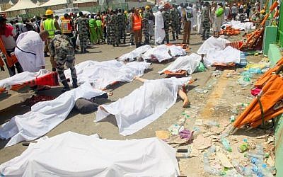 Saudi emergency personnel and pilgrims stand near bodies covered in sheets at the site where hundreds were killed in a stampede in Mina, near the holy city of Mecca, at the annual hajj in Saudi Arabia on September 24, 2015. (AFP/STR)