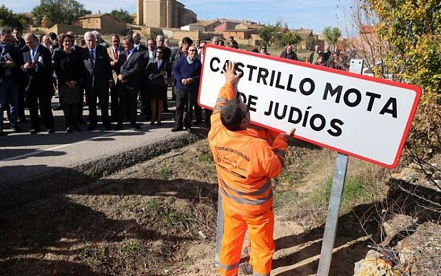Officials look at an employee setting up a road sign reading the new name of Spanish village 'Castrillo Mota de Judios' which means 'Castrillo Mound of Jews'  at the entrance of Castrillo Mota de Judios, near Burgos on October 23, 2015. (AFP PHOTO/ CESAR MANSO)