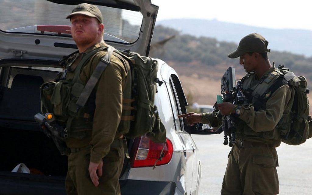 Israeli soldiers inspect a Palestinian car at a checkpoint close to the West Bank village of Beit Furik, east of Nablus, on October 2, 2015, after Palestinian gunmen killed an Israeli couple the night before. (AFP/Jaafar Ashtiyeh)