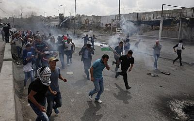 File. Palestinians run from tear gas smoke during clashes with Israeli security forces at the Qalandia checkpoint between Jerusalem and Ramallah in the West Bank, on October 6, 2015. (AFP PHOTO/ABBAS MOMANI)