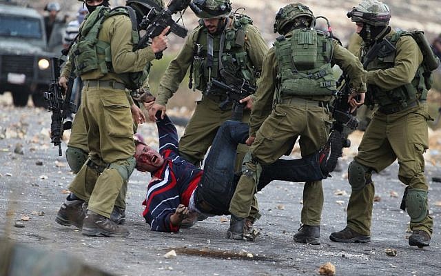 Israeli soldiers detain a Palestinian stone thrower  near Beit El, on the outskirts of the West Bank city of Ramallah, on October 7, 2015. (AFP/ABBAS MOMANI)