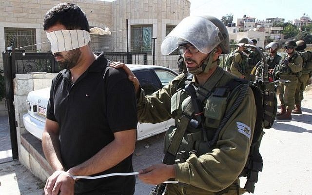 Illustrative: Israeli security forces arrest and blindfold a Palestinian man during clashes in the village of Beit Omar, near the city of Hebron in the West Bank, on October 11, 2015. (AFP/Hazem Bader)