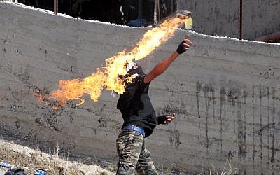 Illustrative: A Palestinian hurls a Molotov cocktail toward Israeli security forces during clashes, near the city of Hebron, in the West Bank, on October 11, 2015. (AFP/Hazem Bader)