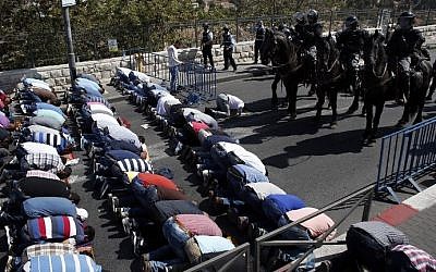 Israeli police stand guard as Palestinian Muslims pray on the streets of the Wadi al-Joz neighborhood in East Jerusalem during the Friday prayers following restrictions by Israeli police preventing Palestinians under 40 years old from entering the Temple Mount, on October 16, 2015. (AFP PHOTO / THOMAS COEX)